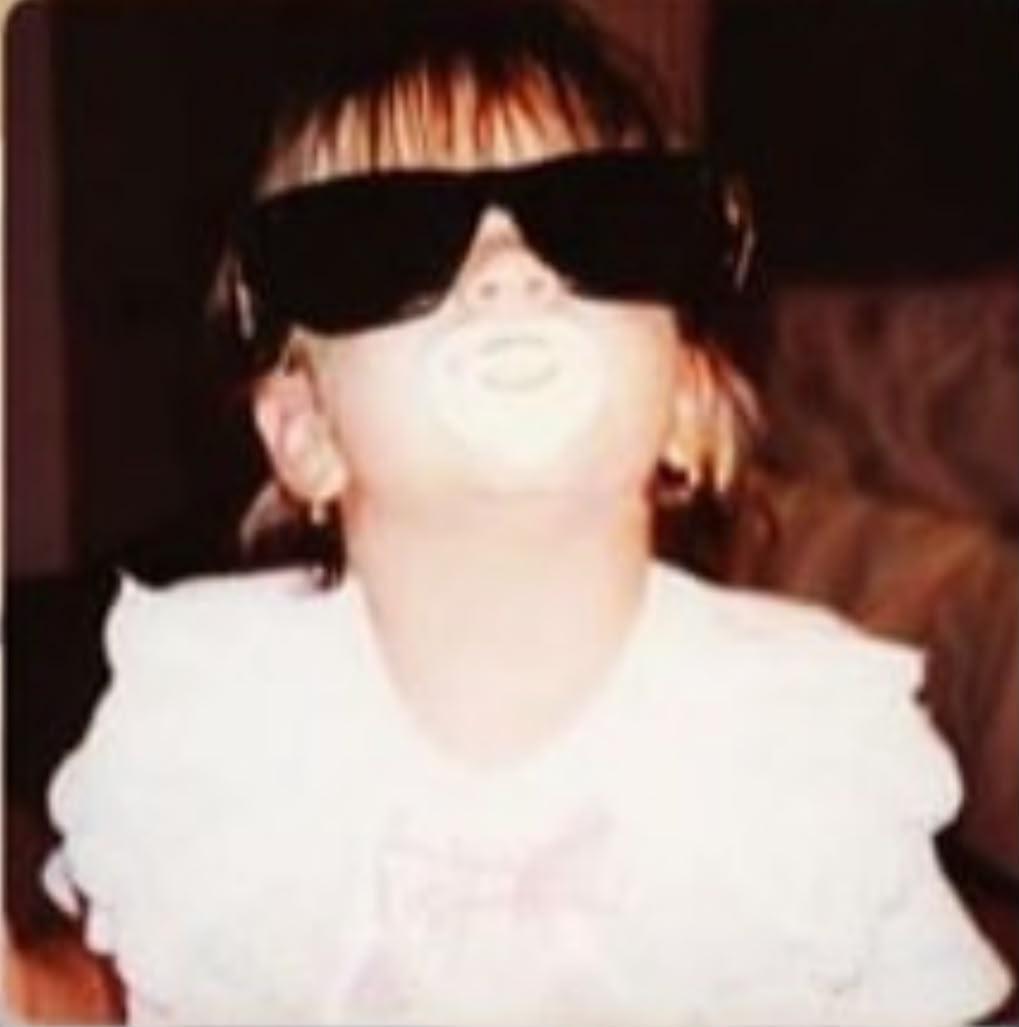 Niña con lentes de sol grandes mirándose al espejo con actitud diva